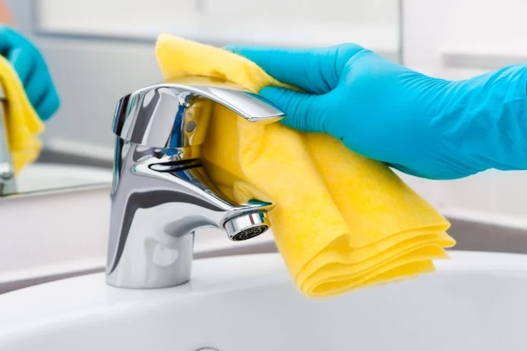 Close up of hand wearing glove cleaning sink tap