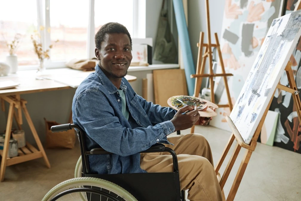 Disabled man in wheelchair painting in art class