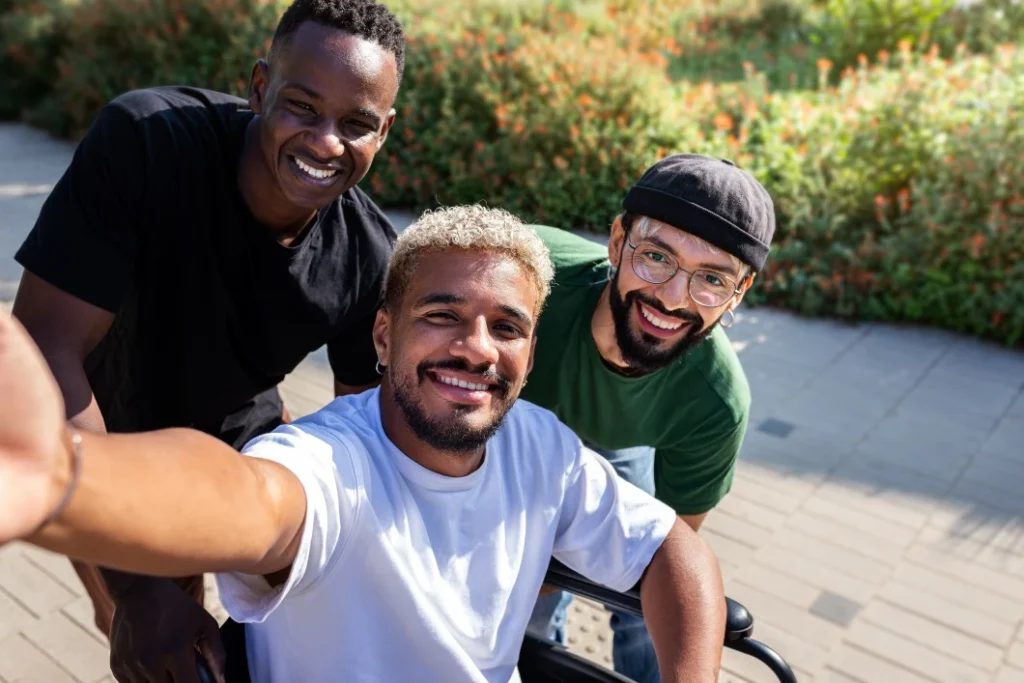 Multicultural friends, one disabled in wheelchair, outside and smiling at camera