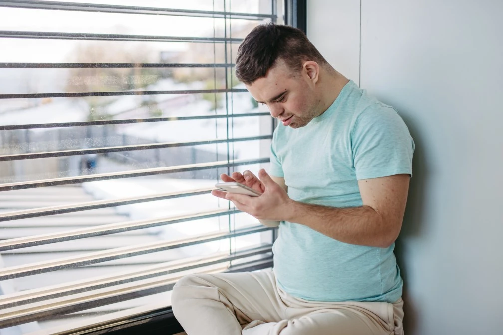 Disabled man with down syndrome using mobile phone to make call