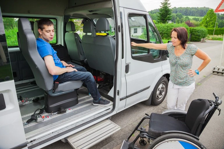 Disabled man in van with support worker about to get out and into wheelchair